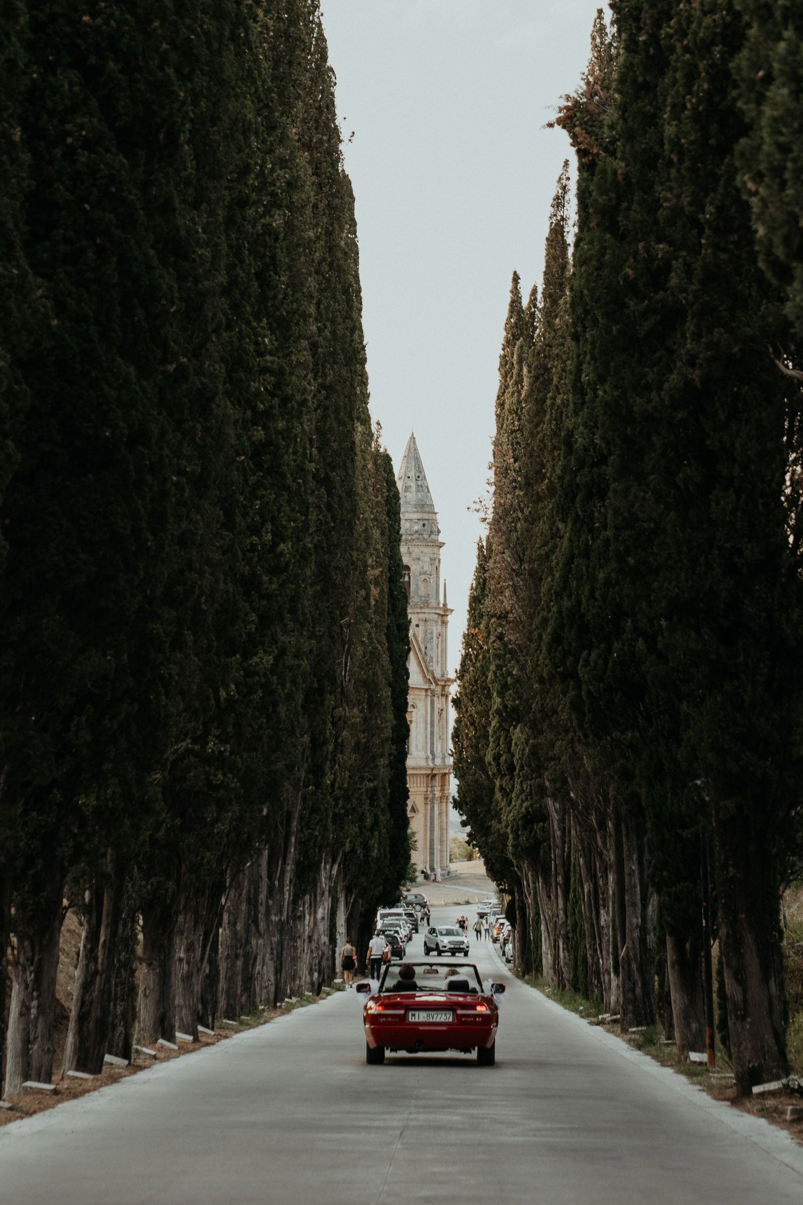 Brautpaarshooting in der Toskana bei einer Auslandshochzeit Auto fährt durch eine Allee