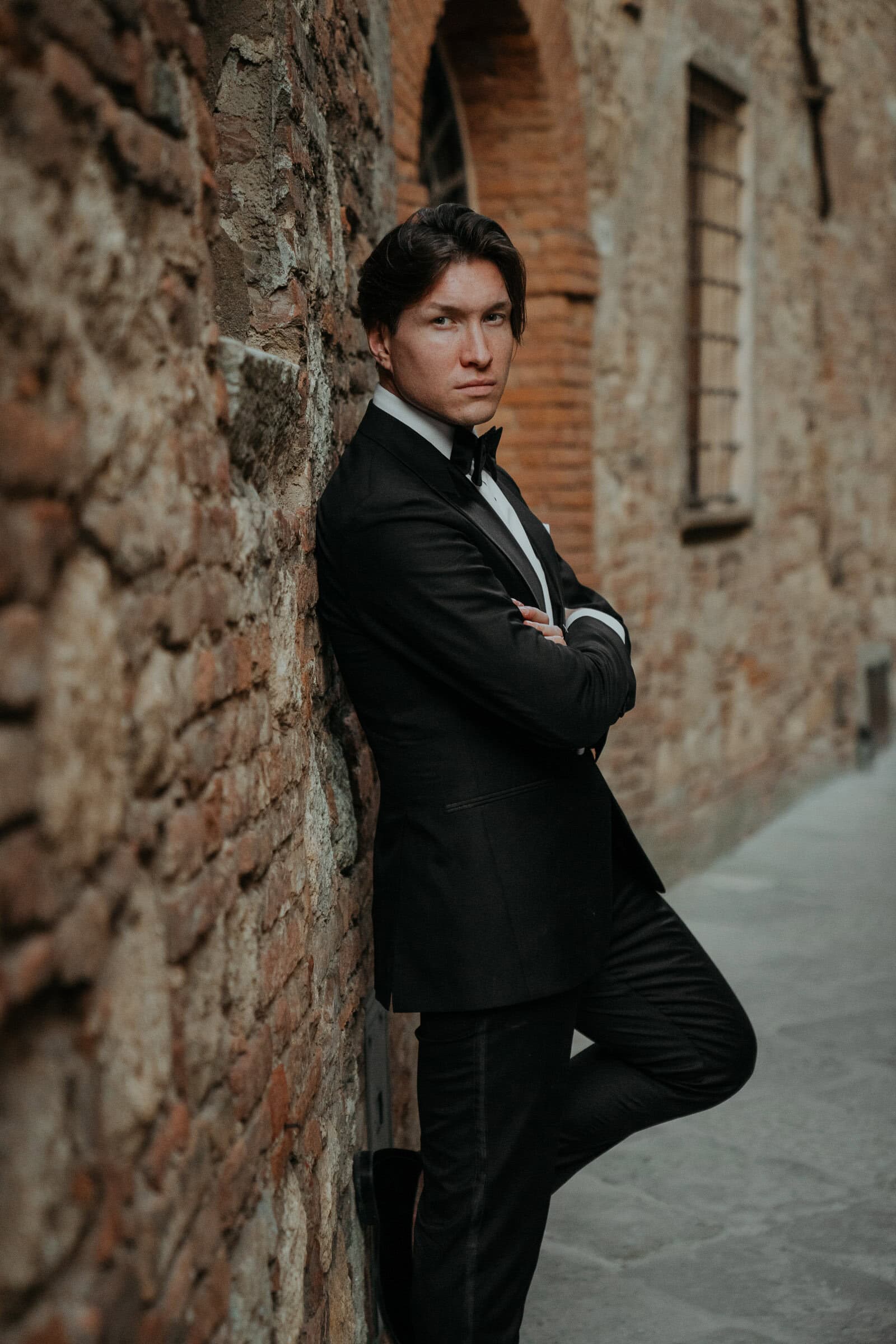 Bräutigam in den Gassen von Montepulciano in der Toskana gelehnt an der Wand